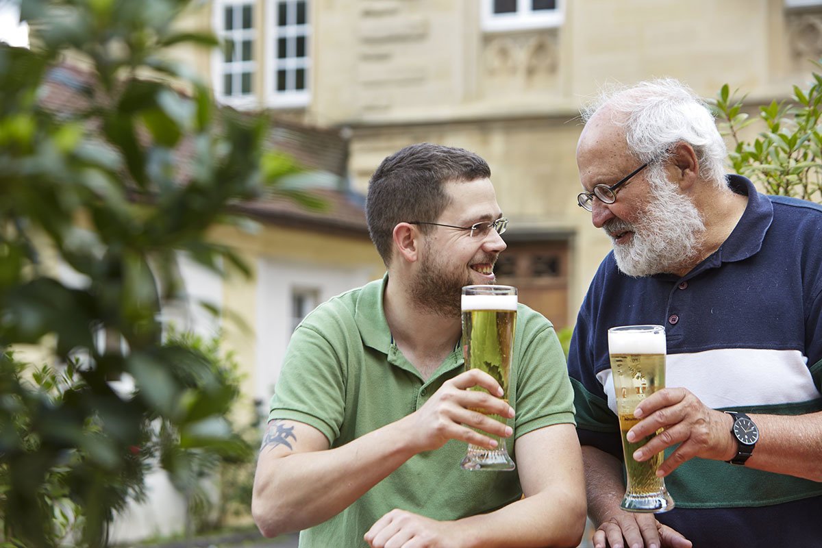 Bewohner und Ehrenamtlicher Mitarbeitende beim Bier trinken