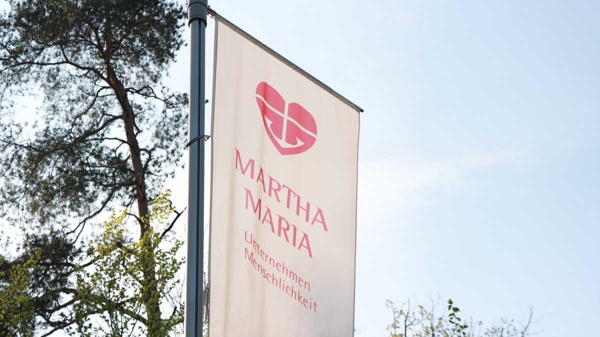 Das Martha-Maria-Logo auf einer Fahne vor einer Einrichtung