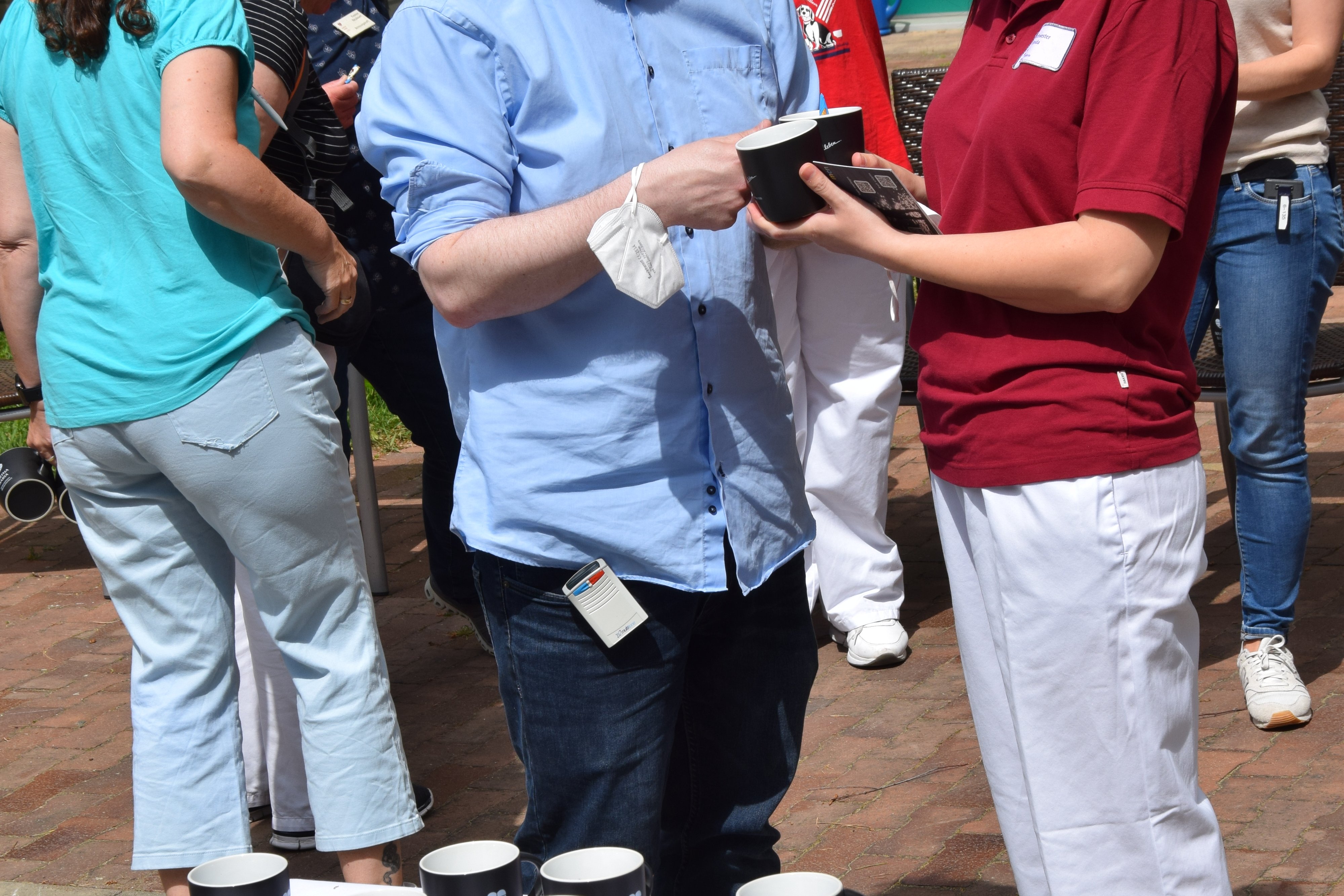 Lächelnde Menschen teilen Tassen bei einer Outdoor-Veranstaltung.