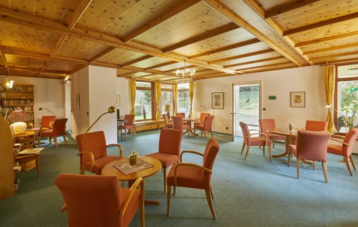 Gemütliches Wohnzimmer in der Klinik Hohenfreudenstadt mit Holzmöbeln und Bücherecke.
