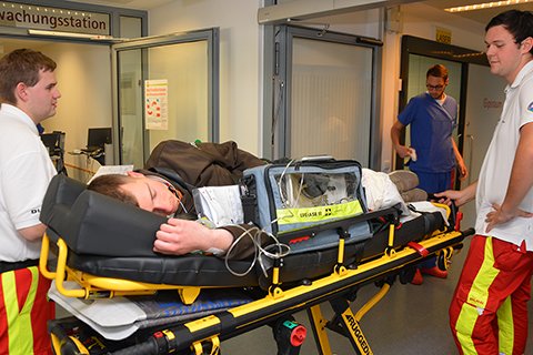 Sanitäter transportieren Patienten auf Trage im Krankenhausflur.