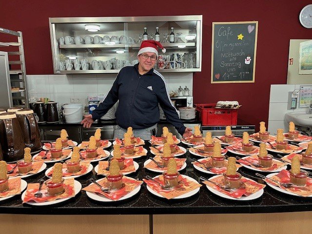 Mitarbeiter im Seniorenzentrum Eckental serviert Weihnachtsdesserts, Tisch dekoriert.
