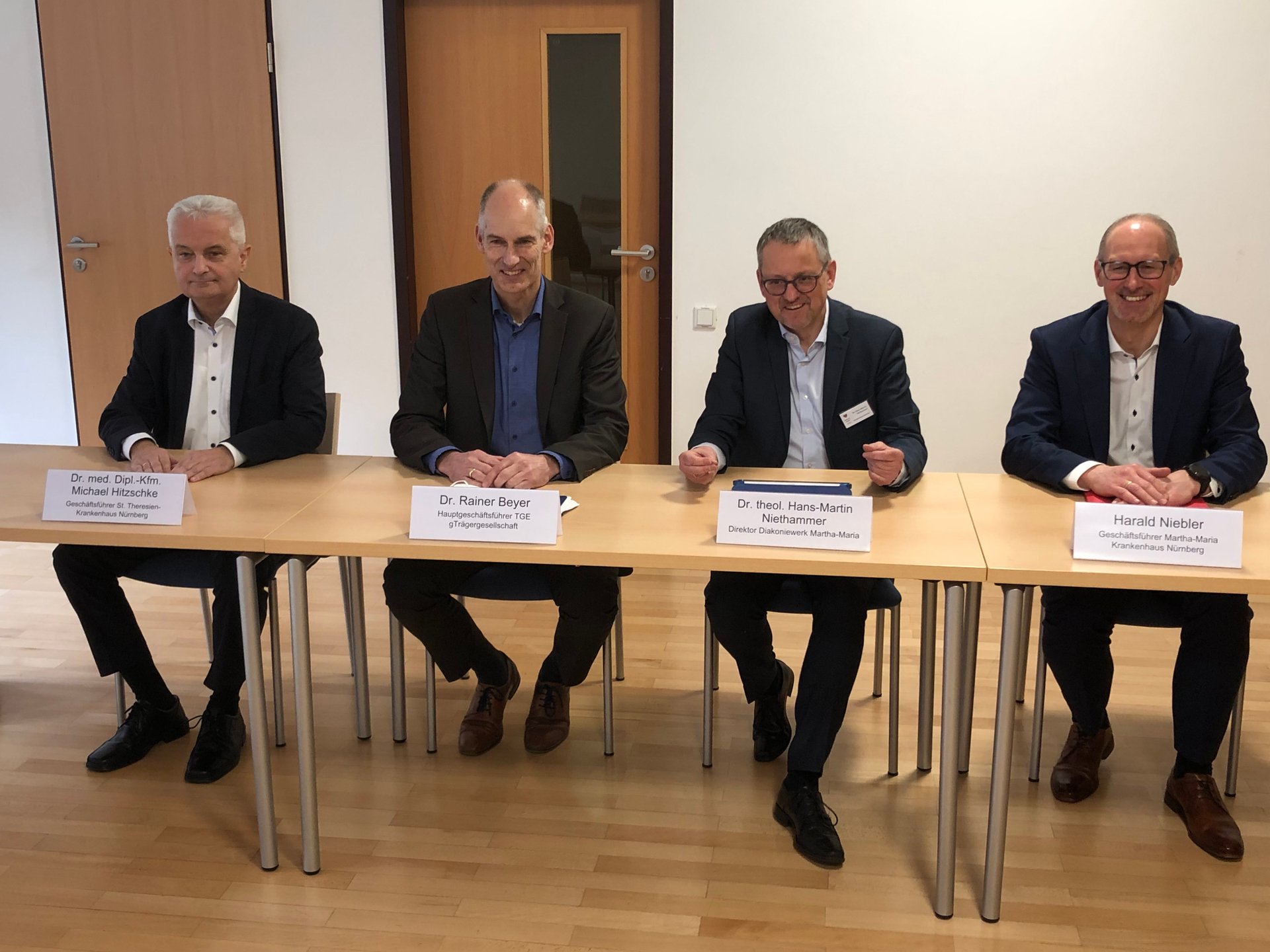 Vier Männer bei einer Konferenz im Krankenhaus Nürnberg sitzend.