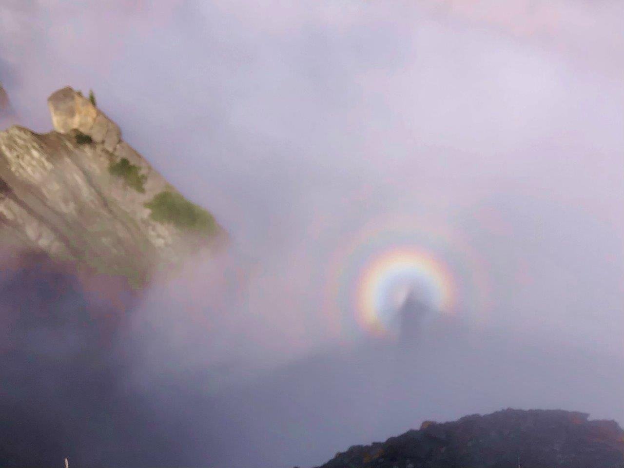 Berglandschaft im Nebel mit Brockengespenst und Regenbogenhalo.