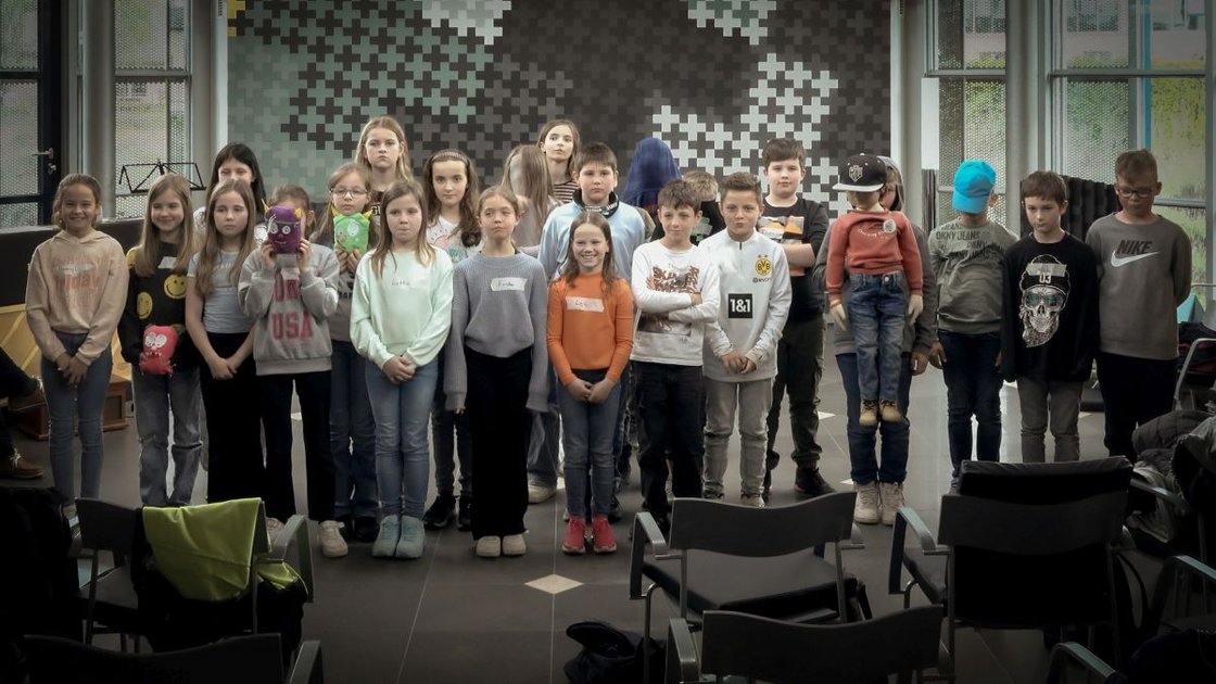 Eine Gruppe Kinder präsentiert stolz selbstgemachte Puppen im Krankenhaus Martha-Maria.