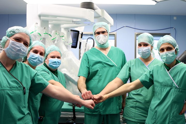 Chirurgenteam in OP-Kleidung, vereint die Fäuste im Operationssaal.