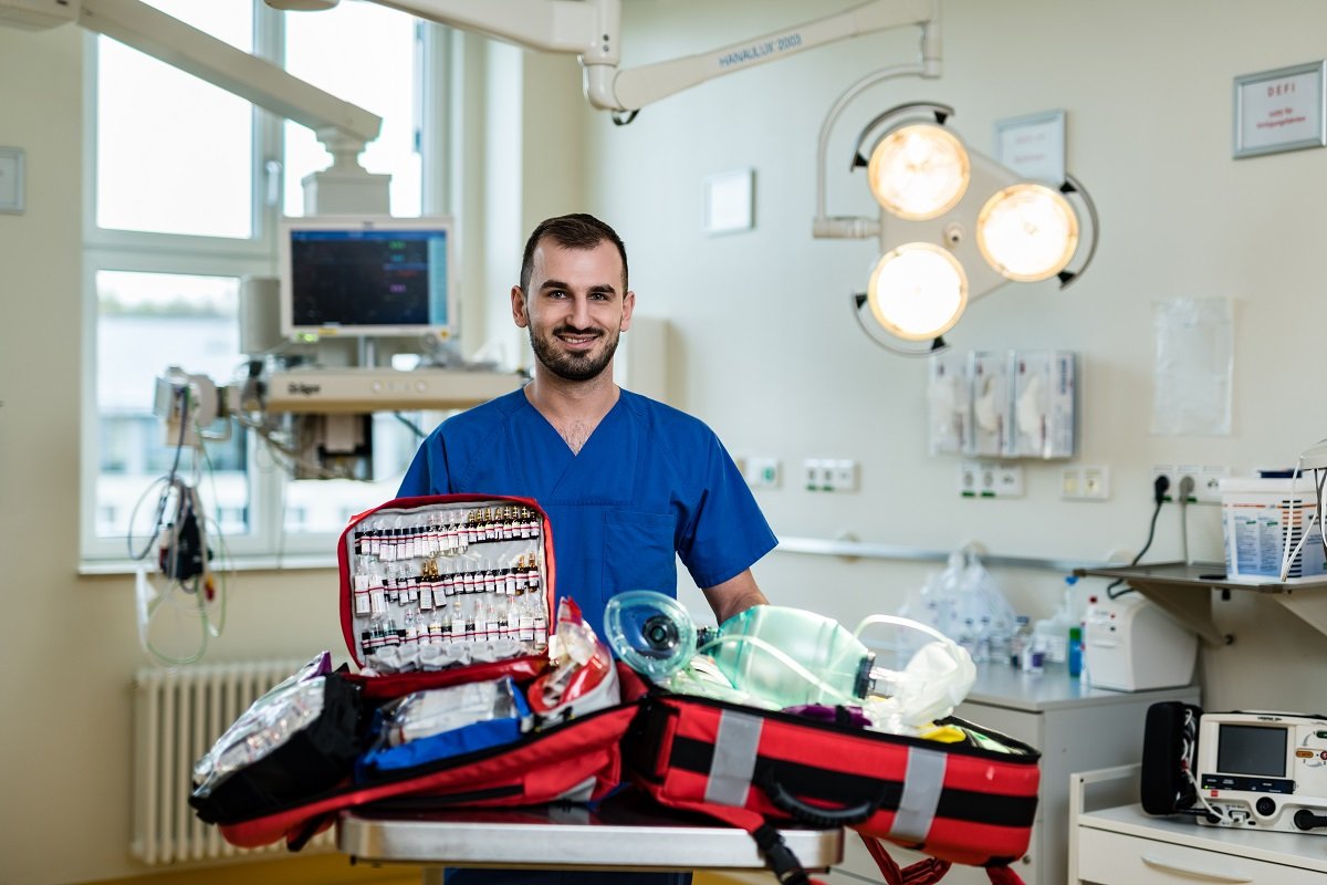 Krankenpfleger in blauer Uniform mit Notfallkoffer im Krankenhaus.