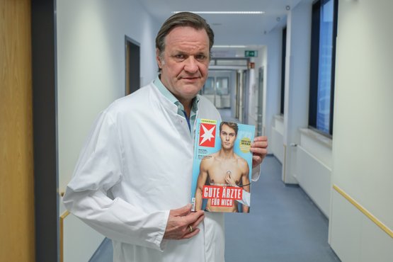 Arzt hält Magazin 'Gute Ärzte' im Krankenhausflur.
