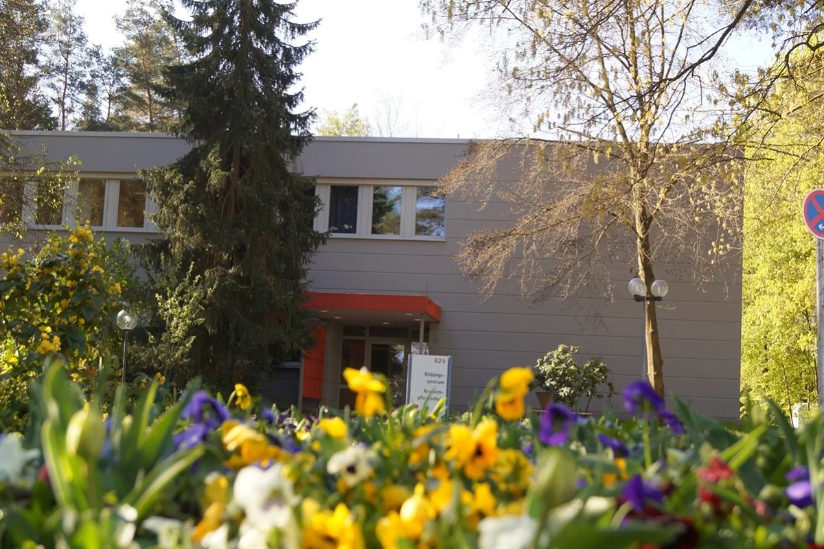 Gebäude des Bildungszentrums mit bunten Blumen im Vordergrund.