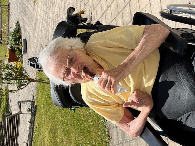 Seniorin im Rollstuhl genießt Eis im Garten des Seniorenzentrums Eckental.