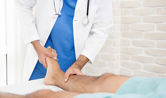 Arzt untersucht Bein eines liegenden Patienten im Krankenhaus.