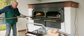 Mann backt Brot im Außenofen des Seniorenzentrums Wüstenrot.