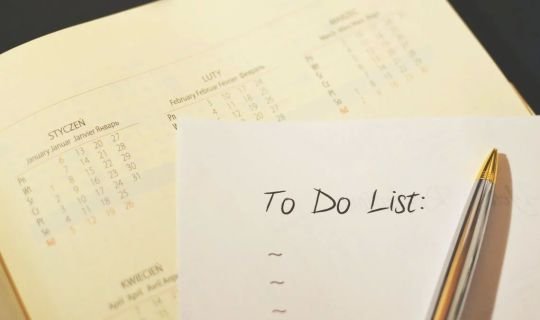 Kalender mit Notizblock und Stift für To-Do-Liste auf Tisch.