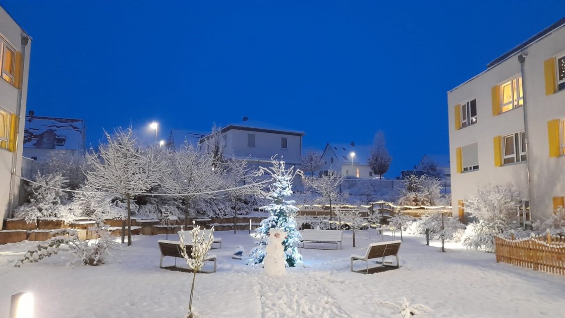 Verschneiter Garten im Seniorenzentrum Eckental, mit beleuchtetem Tannenbaum.
