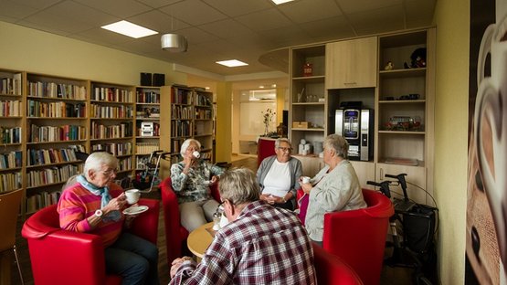 Senioren trinken Kaffee in gemütlicher Runde im Aufenthaltsraum des Seniorenzentrums Wüstenrot.