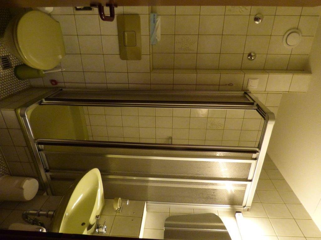 Kleines Krankenhausbad mit Dusche, Waschbecken und Toilette.