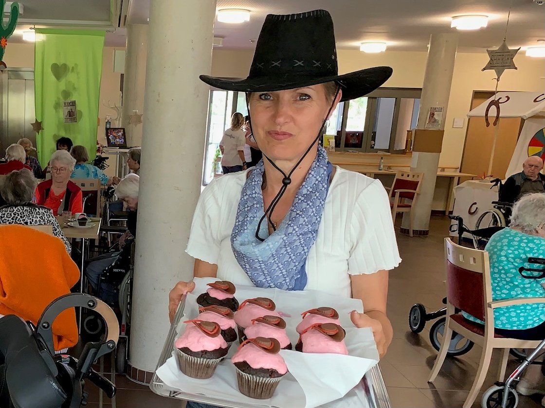 Frau im Cowboyhut serviert Cupcakes im Seniorenzentrum Eckental.