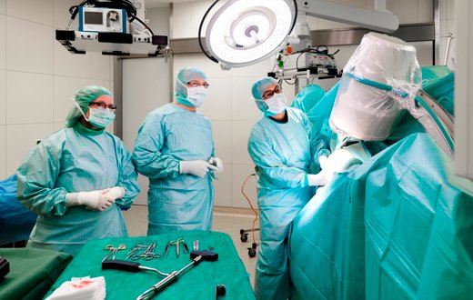 Chirurgenteam bei Operation im sterilen OP-Saal mit medizinischen Geräten.
