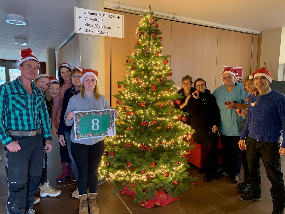 Mitarbeiter des Seniorenzentrums Eckental posieren mit Weihnachtsbaum und Nikolausmützen.
