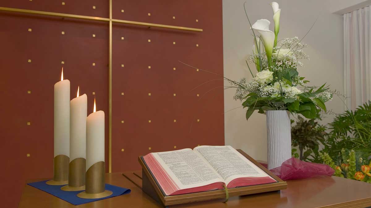 Geöffnete Bibel mit Kerzen und Blumen im Seniorenzentrum.