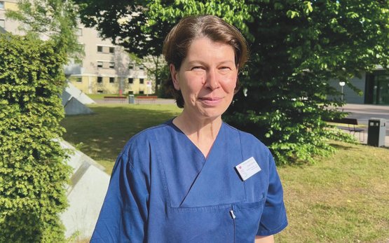 Pflegekraft in blauer Uniform lächelnd im Krankenhausgarten Martha-Maria.