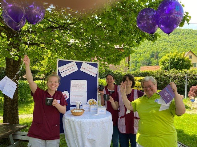 Pflegekräfte feiern den Tag der Pflege mit Ballons und Infotisch im Freien.