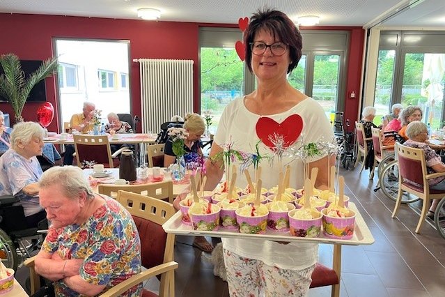 Mitarbeiterin im Seniorenzentrum Eckental serviert Desserts bei einer Feier.