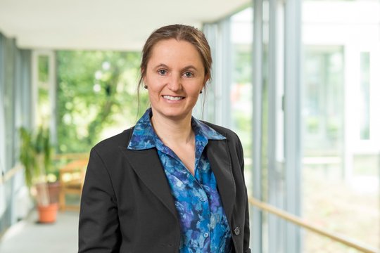 Frau in Geschäftskleidung in einem hellen, modernen Bürogebäude.