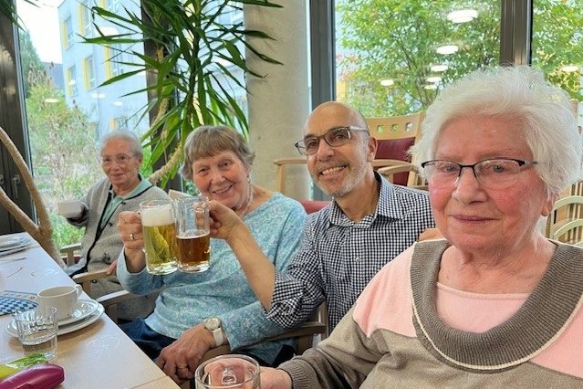 Senioren und Pfleger im Seniorenzentrum Eckental stoßen mit Bier an.