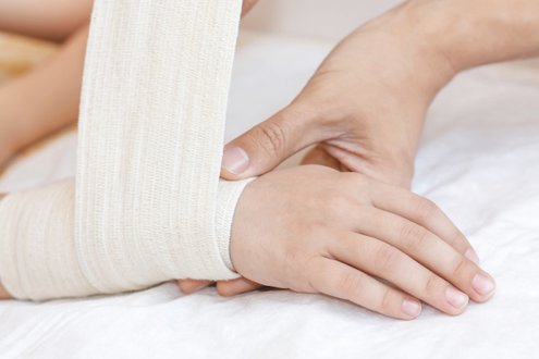 Nahaufnahme einer Hand, die eine Bandage anlegt, symbolisiert Pflege und Unterstützung.