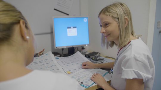Pflegekräfte besprechen Dokumente am Computer im Krankenhaus Martha-Maria.