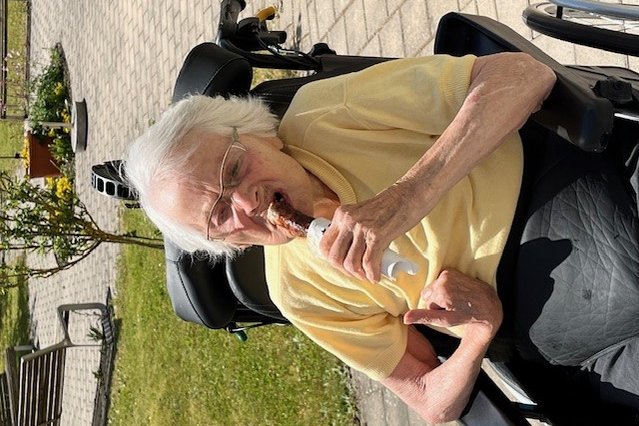 Seniorin im Rollstuhl genießt Eis im Garten des Seniorenzentrums Eckental.