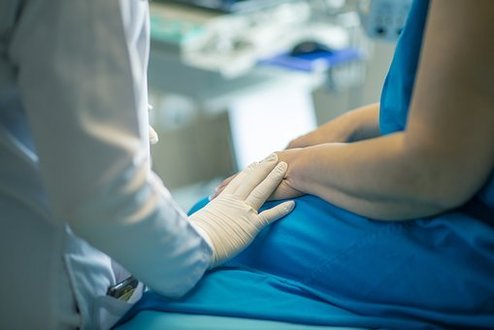 Arzt hält die Hand eines Patienten zur Unterstützung bei schwieriger Diagnose.