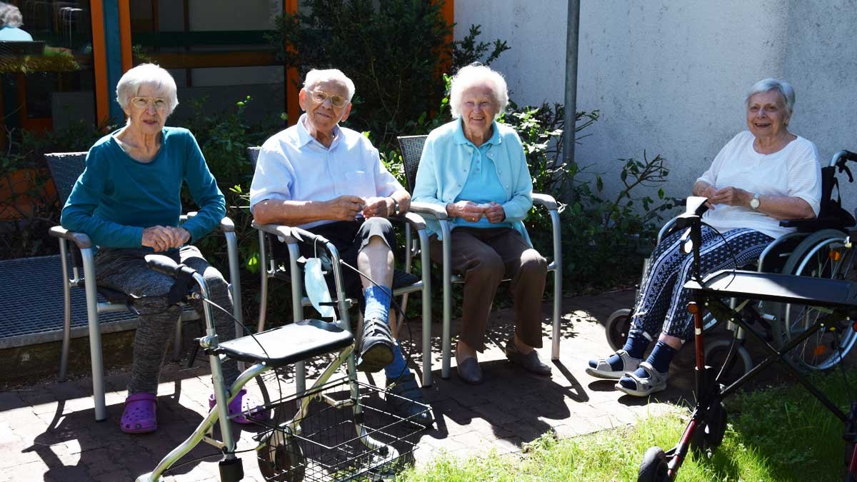 Senioren im Garten des Seniorenzentrums Nürnberg genießen die Sonne.
