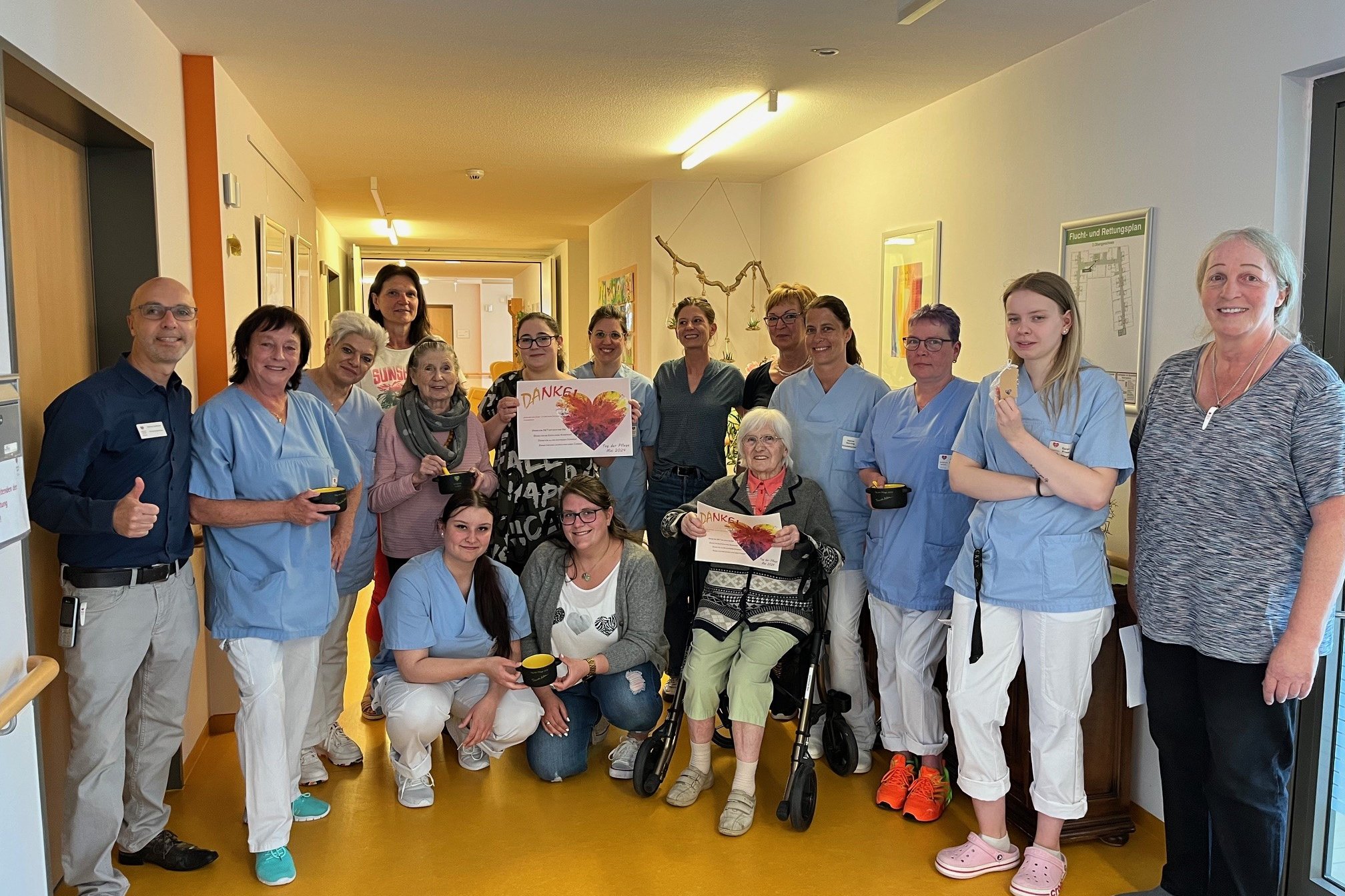 Pflegepersonal und Bewohnerin im Seniorenzentrum Eckental, halten Dankeskarte.