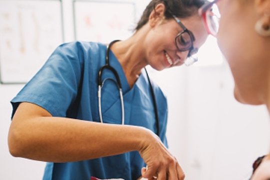 Freundliche Krankenschwester in blauer Uniform betreut einen Patienten im Krankenhaus.