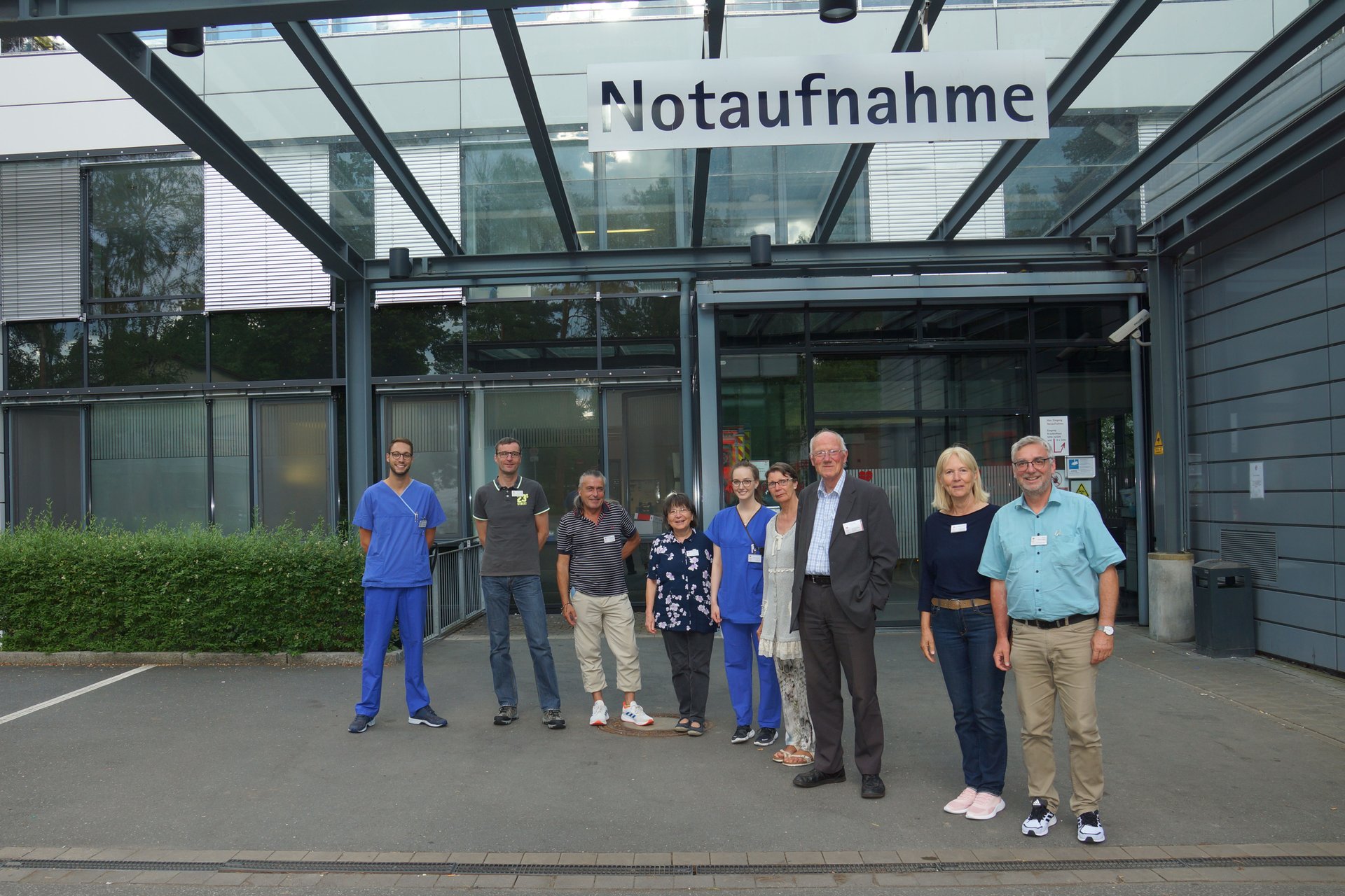 Gruppe von Menschen vor dem Eingang einer Notaufnahme eines Krankenhauses.
