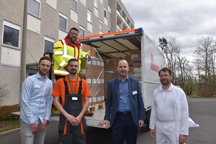 Mitarbeiter vor einem Lieferwagen mit Hilfsgütern, bereit zum Entladen.