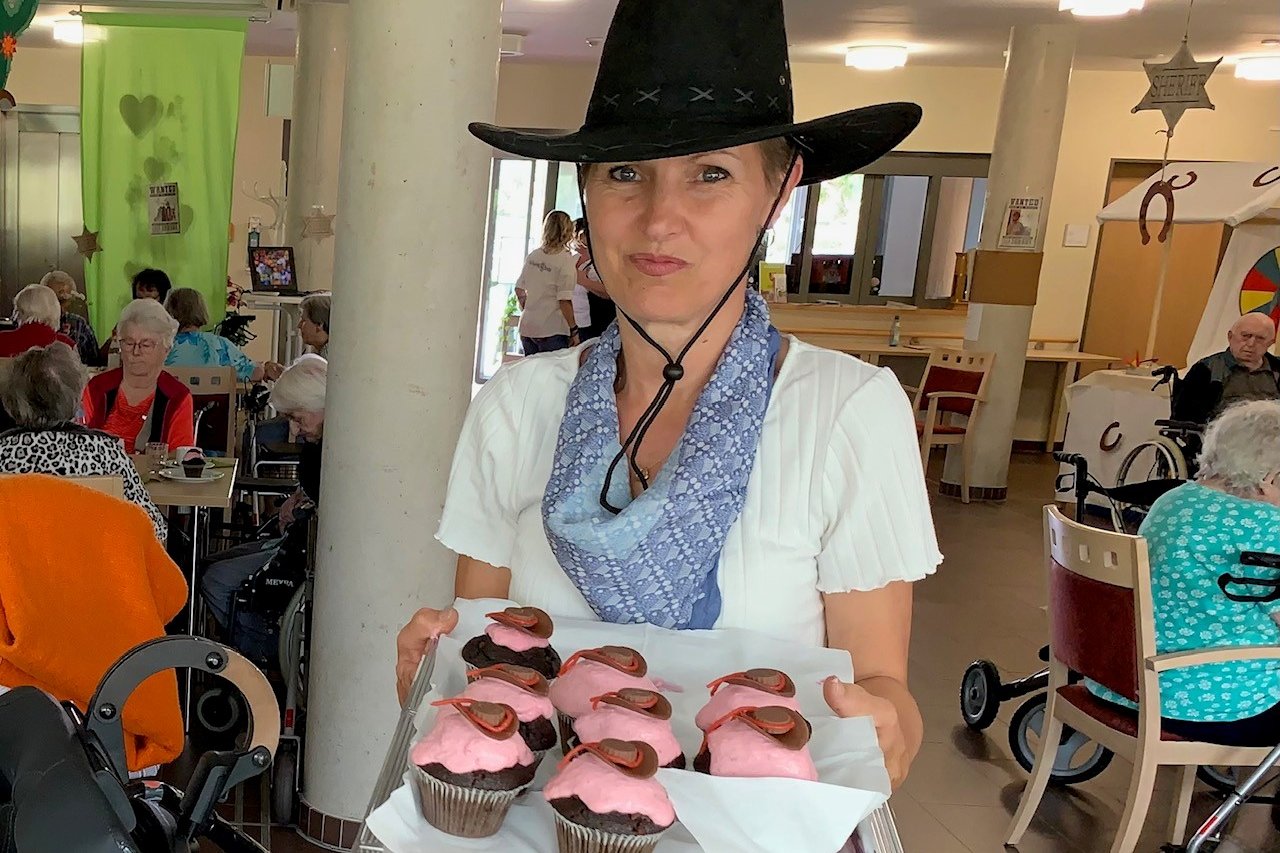Frau im Cowboyhut serviert Cupcakes im Seniorenzentrum Eckental.
