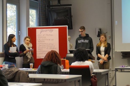 Pflegeschüler präsentieren ein Projekt in einem Klassenzimmer.