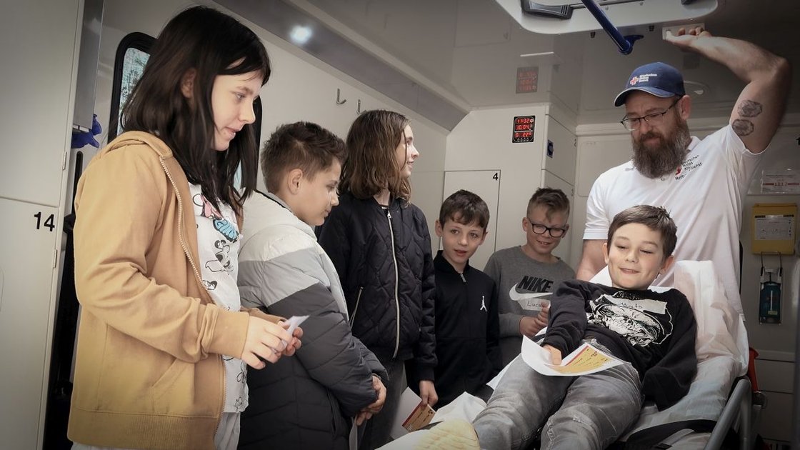 Kindergruppe lernt in Krankenwagen mit Sanitäter, Projekt Jonas will's wissen.