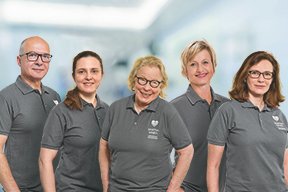 Fünf lächelnde Personen in grauen Poloshirts, MVZ Martha-Maria Nürnberg.