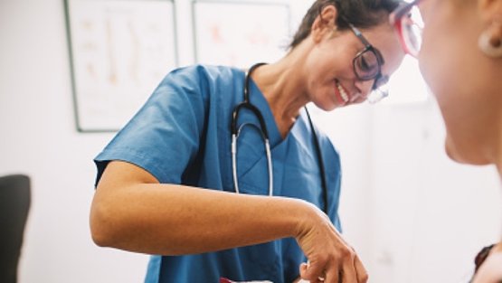 Freundliche Krankenschwester in blauer Uniform betreut einen Patienten im Krankenhaus.