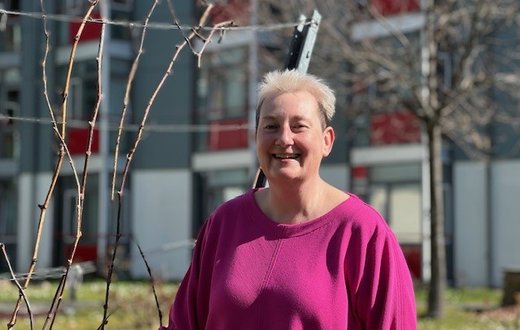 Silke Gehre lächelnd im Freien vor einem modernen Gebäude.