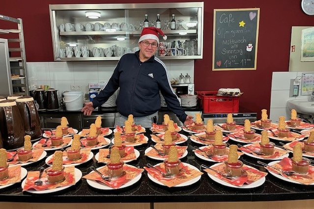 Mitarbeiter im Seniorenzentrum Eckental serviert Weihnachtsdesserts, Tisch dekoriert.