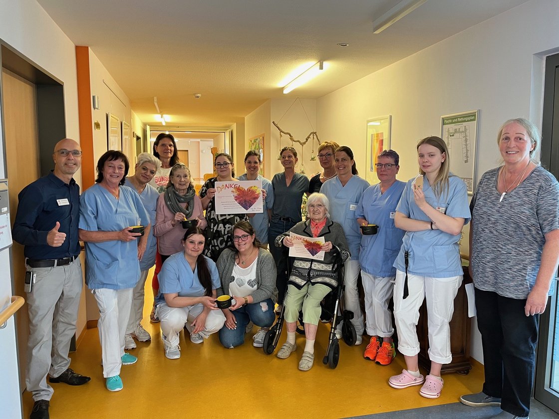 Pflegepersonal und Bewohnerin im Seniorenzentrum Eckental, halten Dankeskarte.