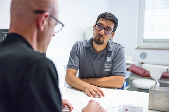Arzt im Gespräch mit Patient in der Urologie-Praxis.