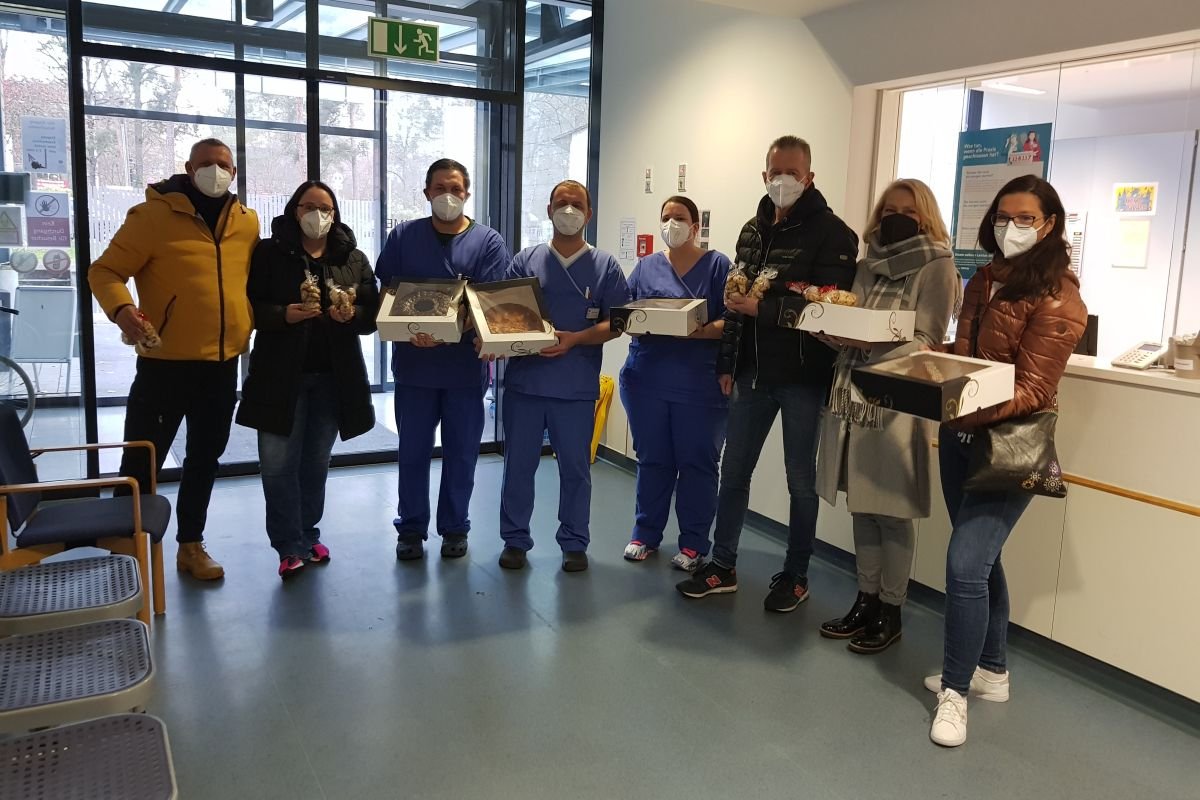 Menschen überreichen Krankenhausmitarbeitern Geschenke in einem Eingangsbereich.