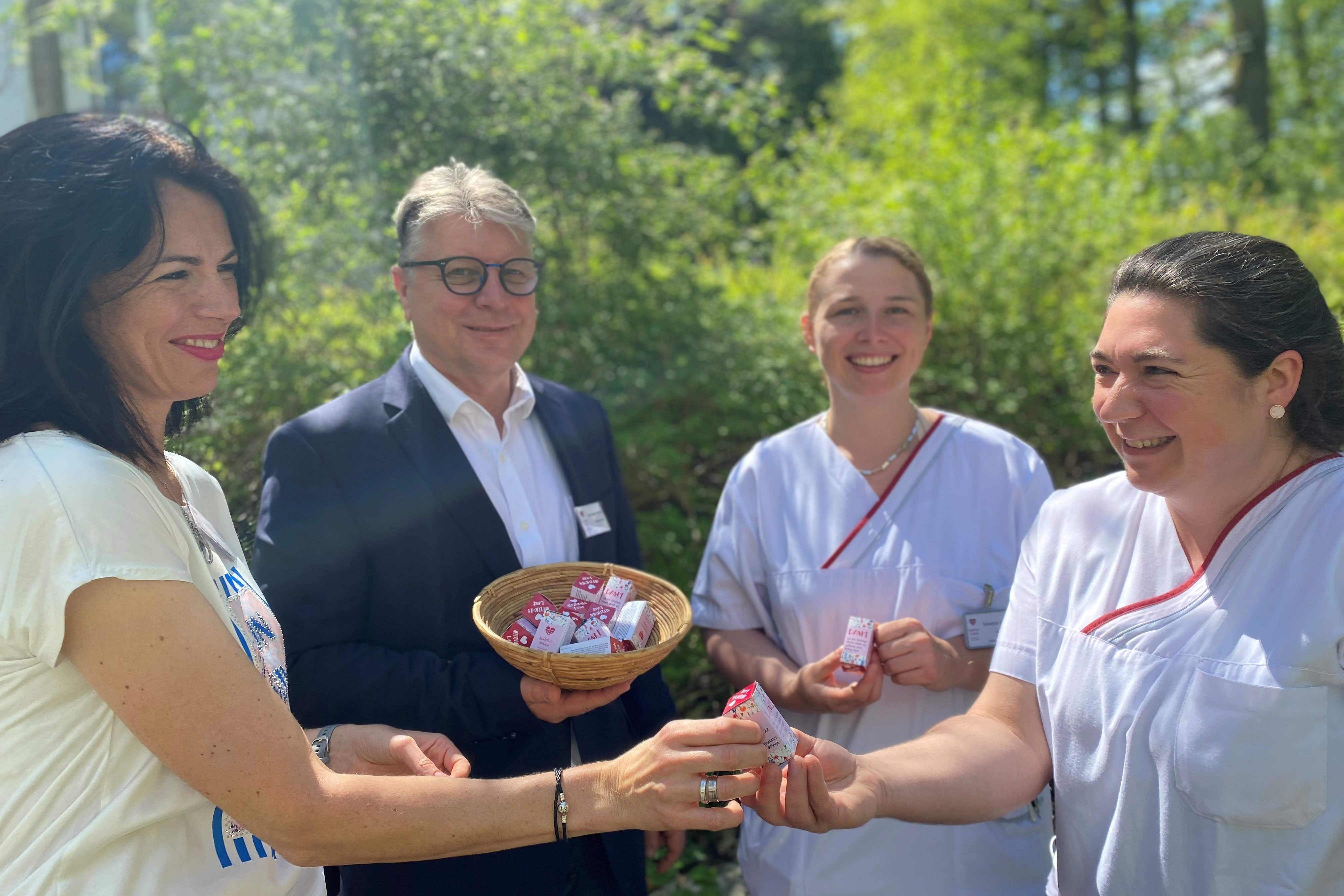 Vier Personen tauschen Geschenke im Freien, lächelnd und freundlich.