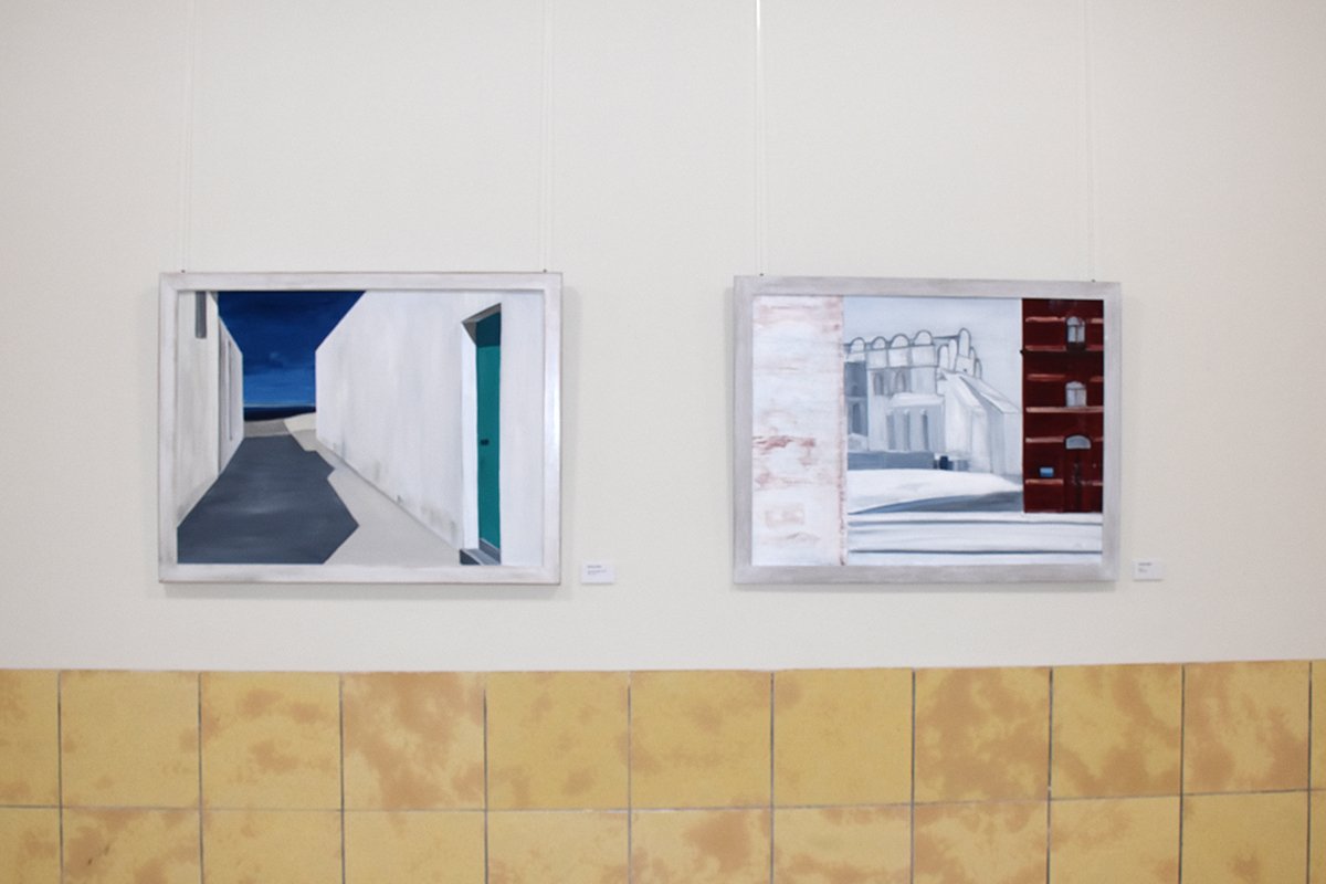 Zwei gerahmte Gemälde an einer Galerie-Wand hängend, moderne Architektur darstellend.